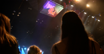 People stand in a stadium and a W&M is seen on the ceiling