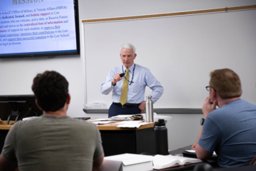 A person stands at the front of a classroom