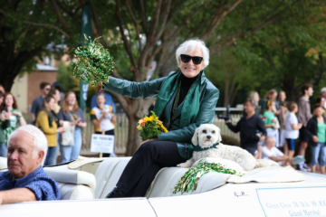 Glenn Close and her dog sit on the back of a convertible and wave to the crowd