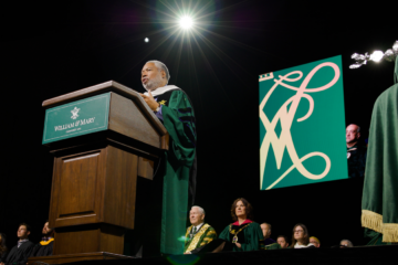 A person in academic regalia stands at a podium.