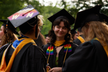 People wearing academic regalia talk with each other
