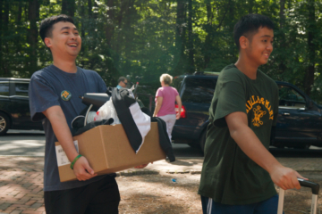 Two people carry boxes.