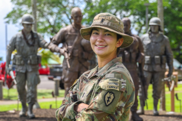 1st Lt. Mackenzie Corcoran ’21 wears a military uniform and stands in front of a monument.