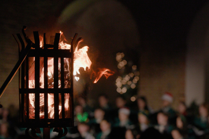 A fire blazes in a torch while a choir sings in the background.