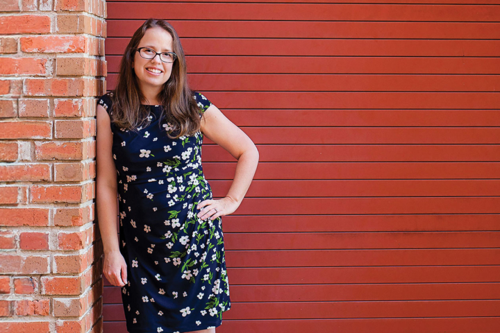 Lori Palen stands next to a red wall.