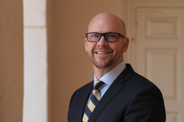 Everton, the new associate vice president for public safety, standing in from of the Wren building, wearing glasses, a suit and a striped tie.