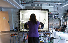 Student with arms in lighted work box as they working with magnets