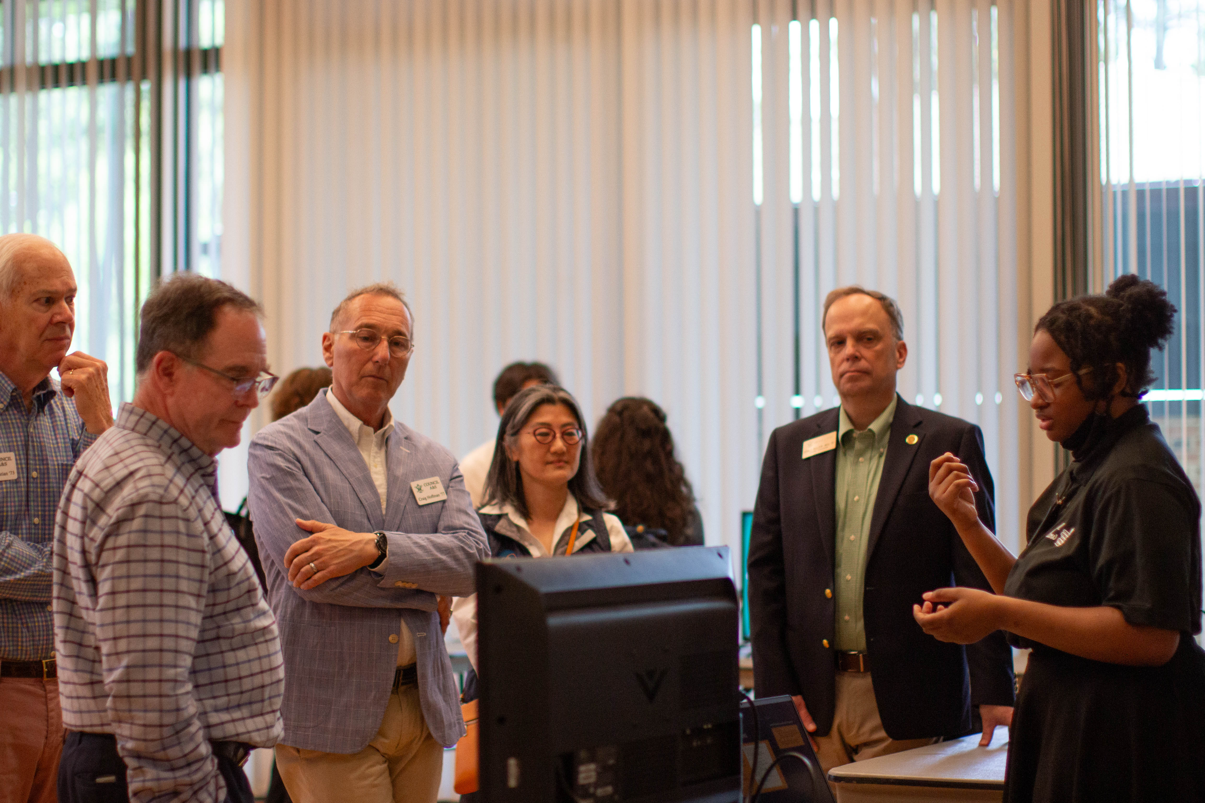 Rin Braxton '26 (far right) discusses methods of transcription in socio-linguistic research with members of William & 玛丽's Council of Arts & Sciences in a digital poster session in the 4th annual WMSURE Research Conference held April 12 in Sadler. (Photo by Tess Willett)