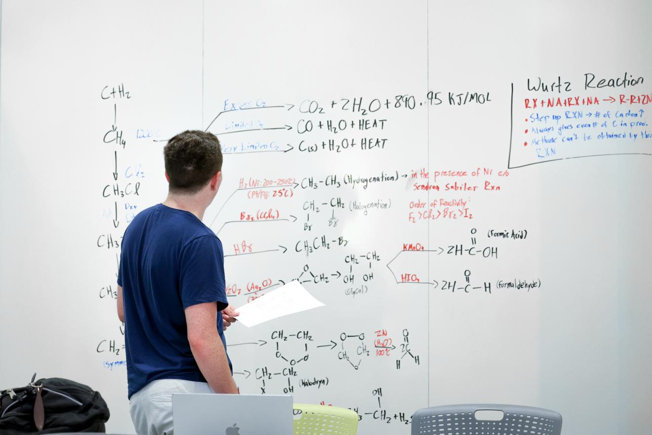 William & 玛丽 organic chemistry student writing equations on a whiteboard