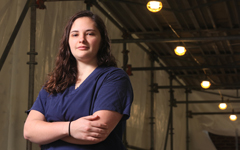 A nurse in scrubs crosses her arms