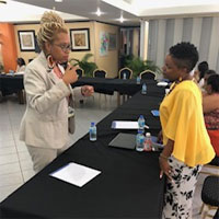 Omiyẹmi Artisia Green (right) talks with an attendee while presenting at a conference in Trinidad and Tobago. (Photo by Shaunté Newby)