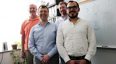 Team of computer scientists stands in front of whiteboard