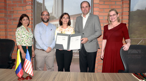 Several people pose for a photo together with two holding up a document