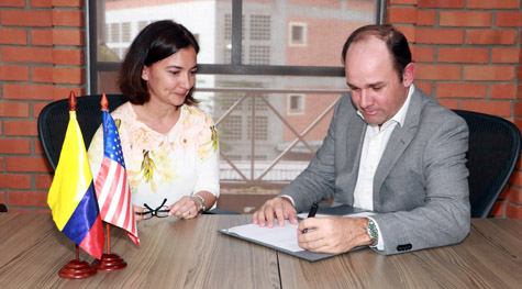 One person watches another sign a memorandum of understanding