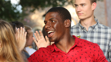 A new student smiles while walking through the greeting line