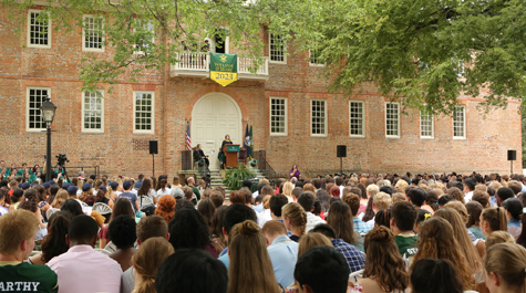 A crowd of students sitting in chairs facing the Wren Building