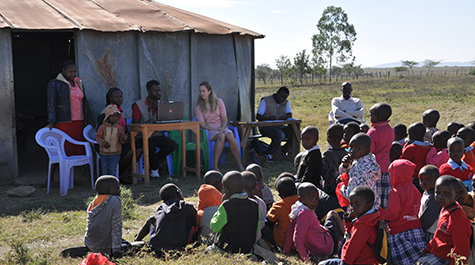 Carrie Dolan is pictured surrounded by a group of young children. She has logged enough time investigating health care issues in the world’s remote locations, from Jamaica to Kenya, to be named a Fellow of the Explorers Club.  