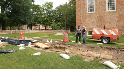 Two people stand in a construction area with the Great Hall visible in the background