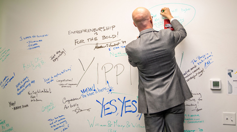 A person writes on a wall where other people have written