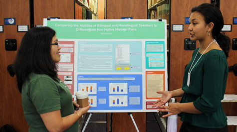 Two students stand by a poster in a library