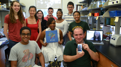 Shantá Hinton sits in the center of her summer lab students, holding an artist’s rendering of STYX.
