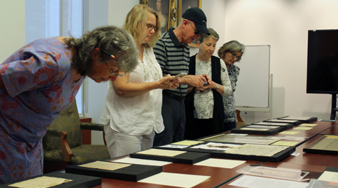 People look at books and other materials spread out on a table