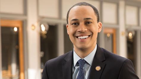 Jay Jones wearing a suit and smiling at the camera