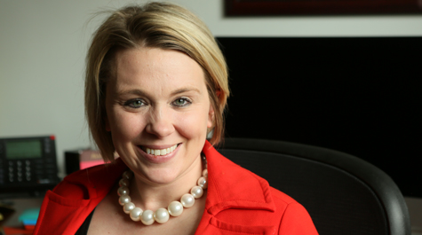 Meredith Kier wearing a red suit jacket and sitting in an office
