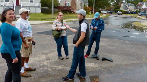 People stand in a street with flooding visible in the background
