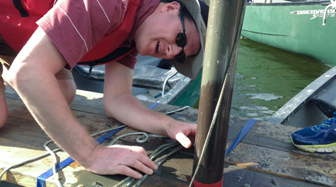 Geologist Jim Kaste inspects a sediment core fresh and dripping from the bottom of Lake Matoaka. 