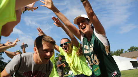 President Katherine Rowe and orientation aides form a hand canopy as a new student passes underneath