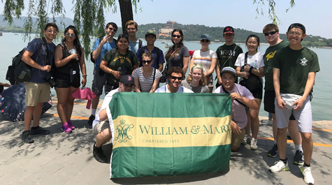 Students pose for a photo together on a beach and holding a William & 玛丽 flag