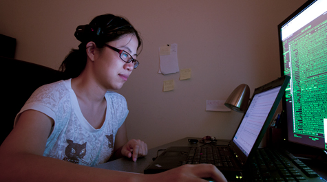 A student writes computer code on a desktop