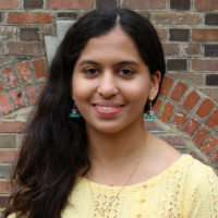 A student standing in front of a brick wall