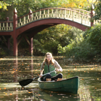 A person paddles a canoe in the Crim Dell pond