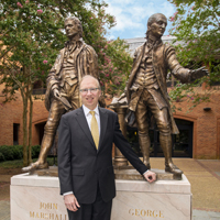 Dave Douglas stands by a statue in front of the law school
