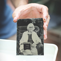 A hand holds up a black and white photo of a woman