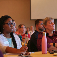 People sitting at tables listening to a speaker