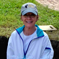 Gail smiles at the camera from an archaeological dig site