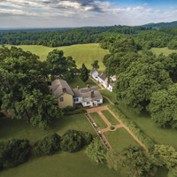 An aerial view of a house surrounded by trees and mountains