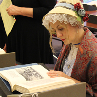 A person dressed in period clothing looks at a book