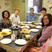 Students sitting around a dinner table together smile at the camera