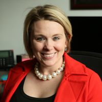 Meredith Kier wearing a red suit jacket and sitting in an office