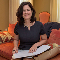 Katherine Rowe sits on a couch with a book on her lap