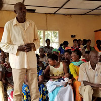 A man stands among people seated around him