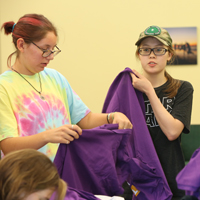 Two students unfold shirts