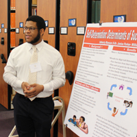 A student stands next to a poster board