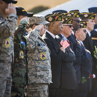 Veterans and military members in uniform salute and hold a flag