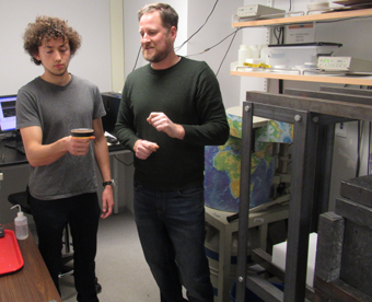 Paul Volante ’20 shows how a petri dish of honey sits atop a gamma detector as Jim Kaste explains the science of the gamma lab. (Photo by Joseph McClain)