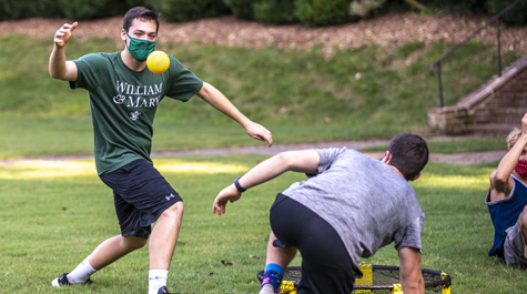 Students wearing masks play spikeball